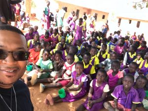 man posing in front of a group of schoolchildren